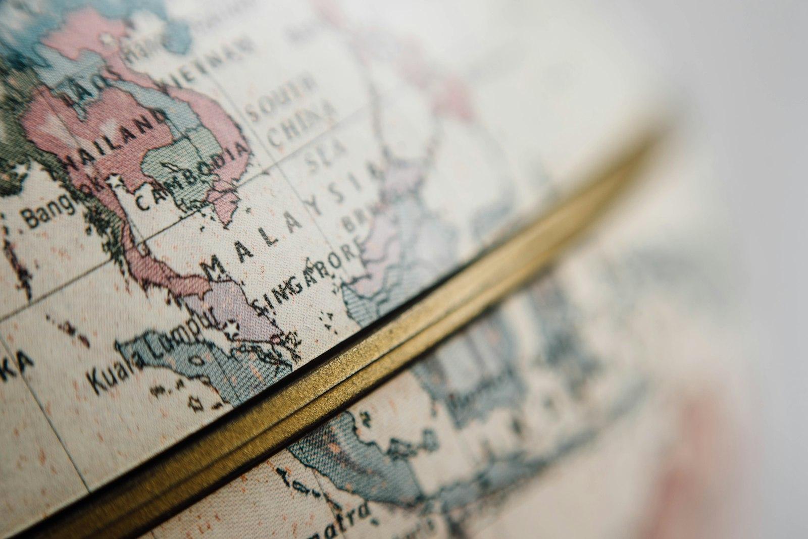 A macro photograph showing a detailed closeup of a physical globe with a golden-colored equator line