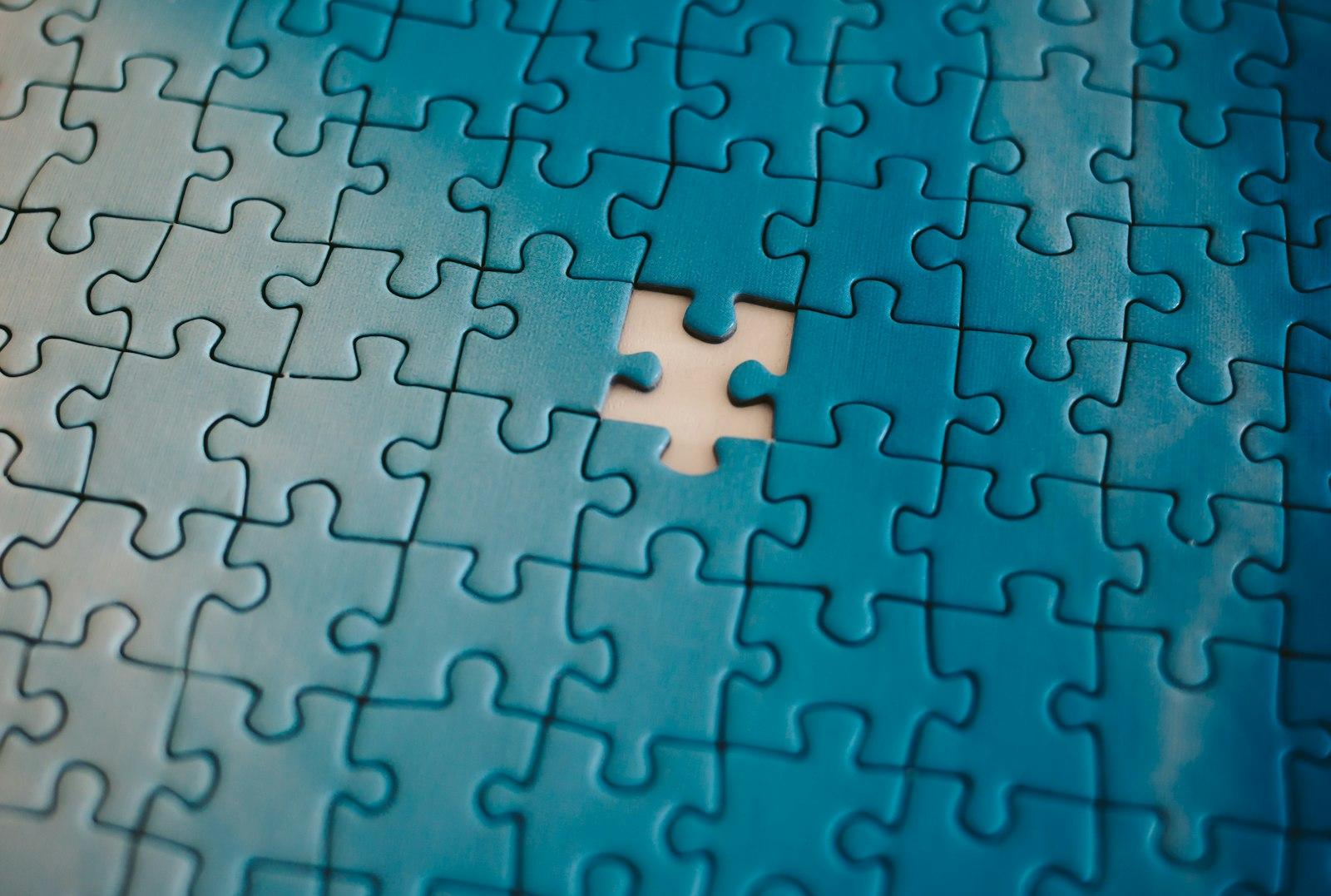 Colorful puzzle pieces in blue, pink, and purple tones with one missing piece