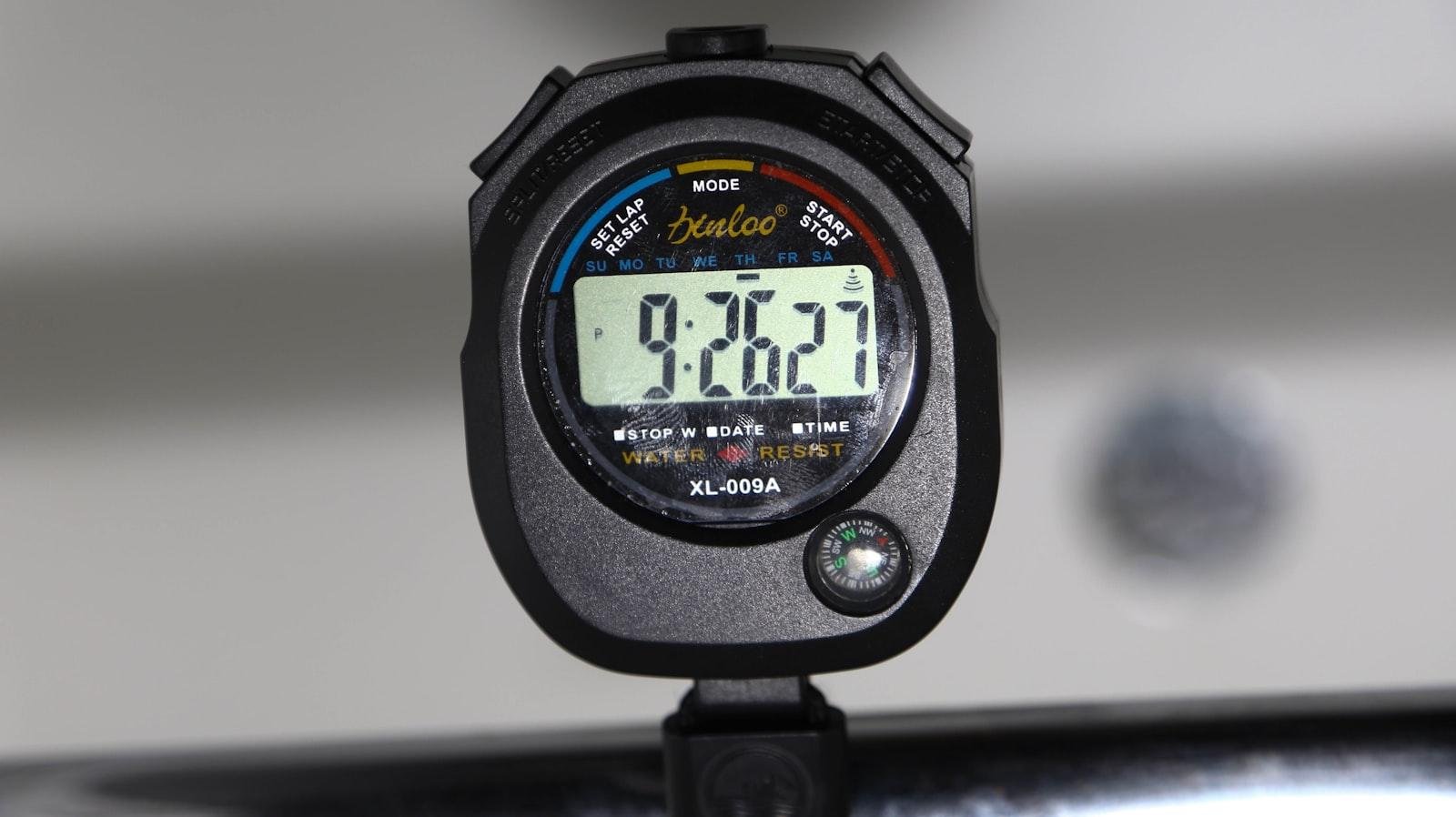 Close-up of a black digital stopwatch displaying a running time, mounted on a stand