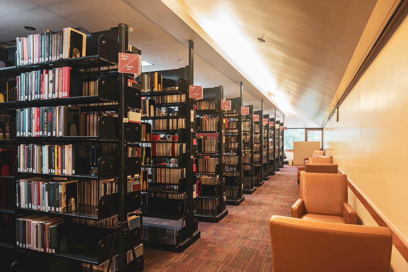 Interior view of multiple library shelves stacked with books, featuring glass panels and architectural elements