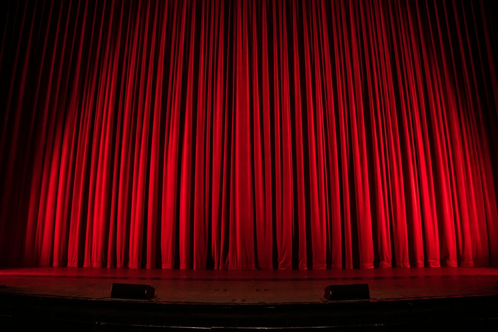 Close-up view of deep red theater curtains with dramatic folds and texture