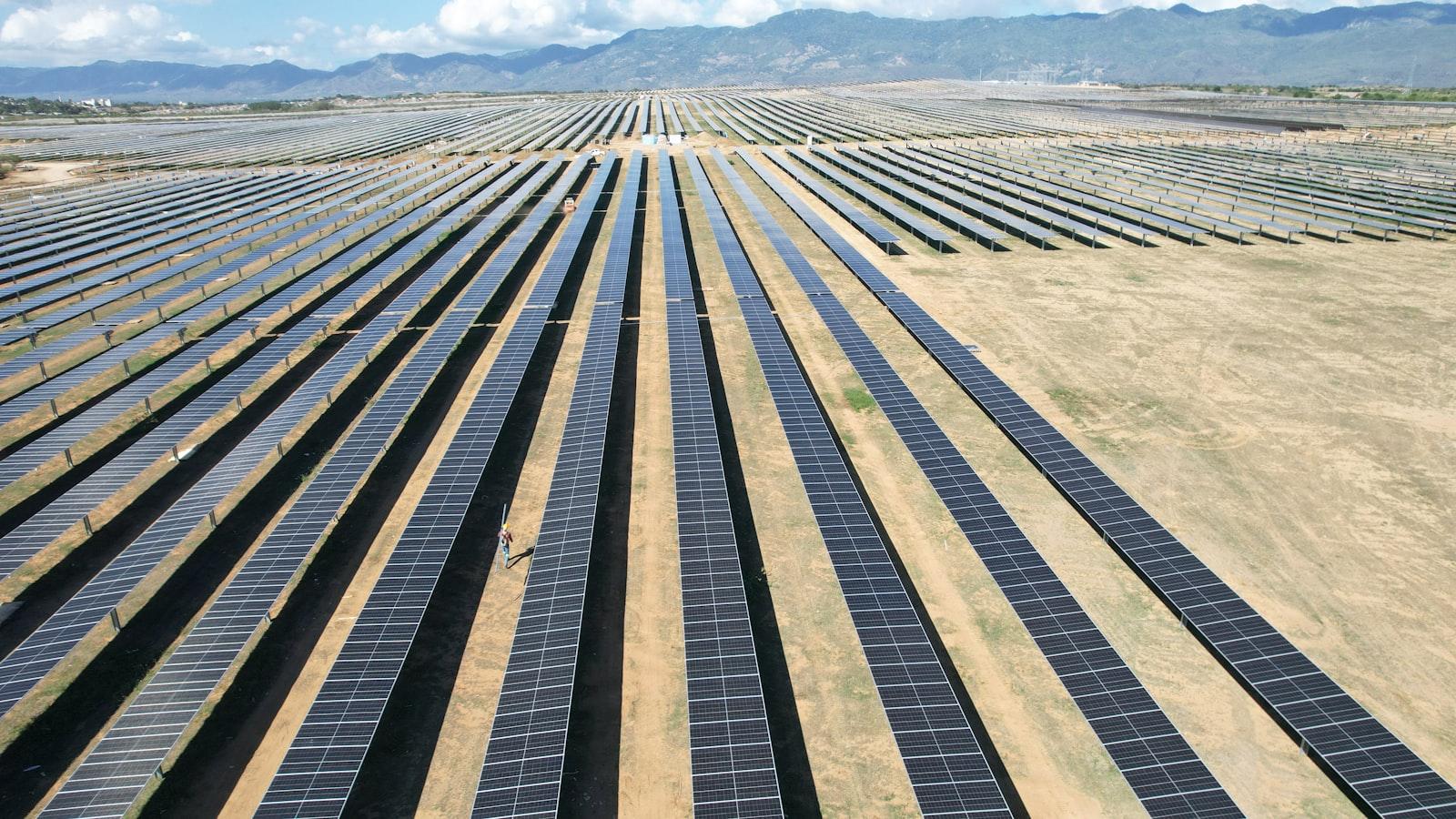 A large field of solar panels stretching across a desert landscape